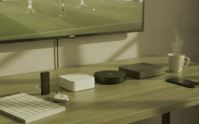 Five streaming devices, a notebook scoring grid and a stopwatch in front of a TV showing a football match