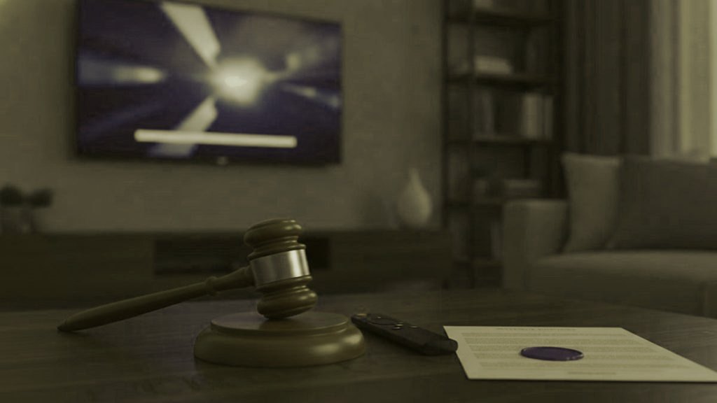 A judge gavel, a streaming remote and a sealed document on a coffee table in front of a TV