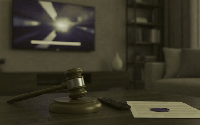 A judge gavel, a streaming remote and a sealed document on a coffee table in front of a TV